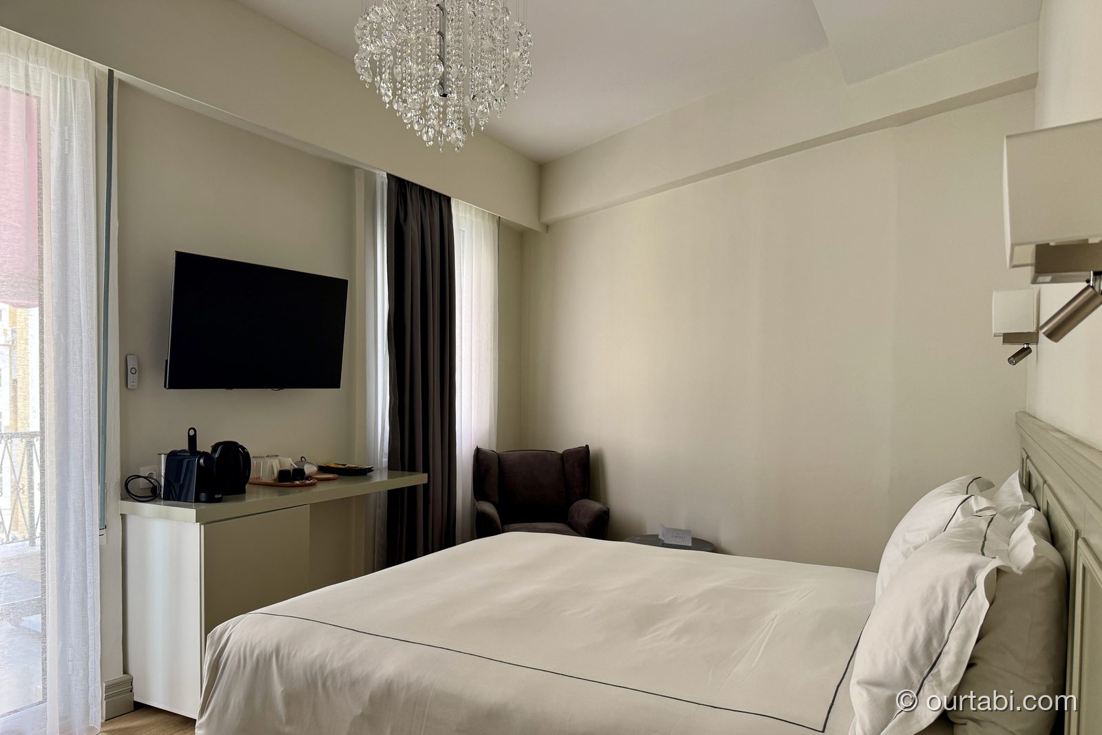 AthenSun Luxury Suitesの客室全景。ベッドとシャンデリアとバルコニーへの窓