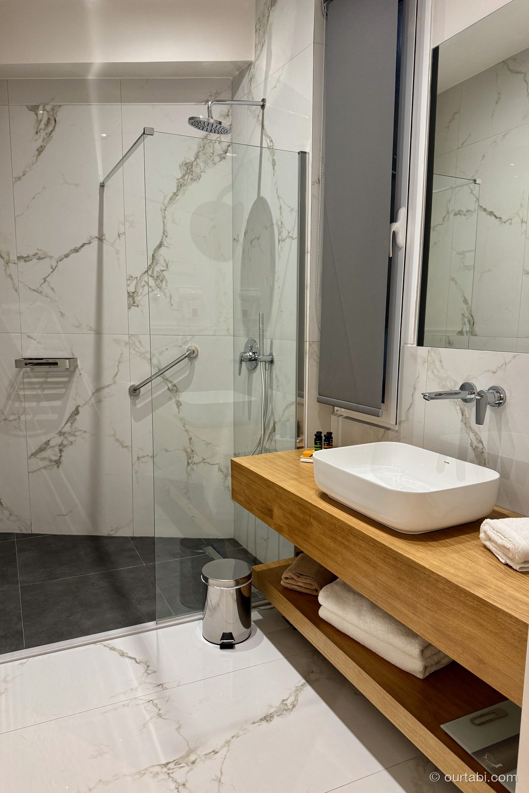 AthenSun Luxury Suitesのバスルーム。大理石調のタイルとガラス張りのシャワー