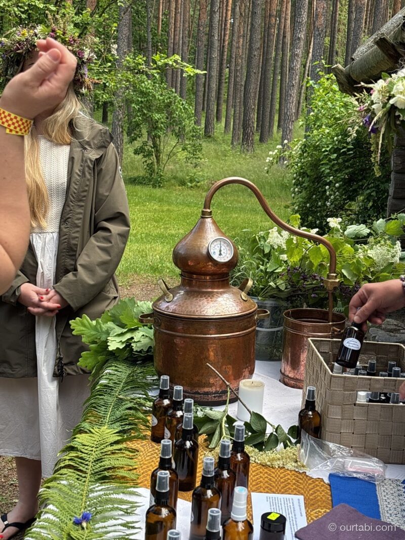 銅製の蒸留器と、ハーブのボトルが並ぶ屋台