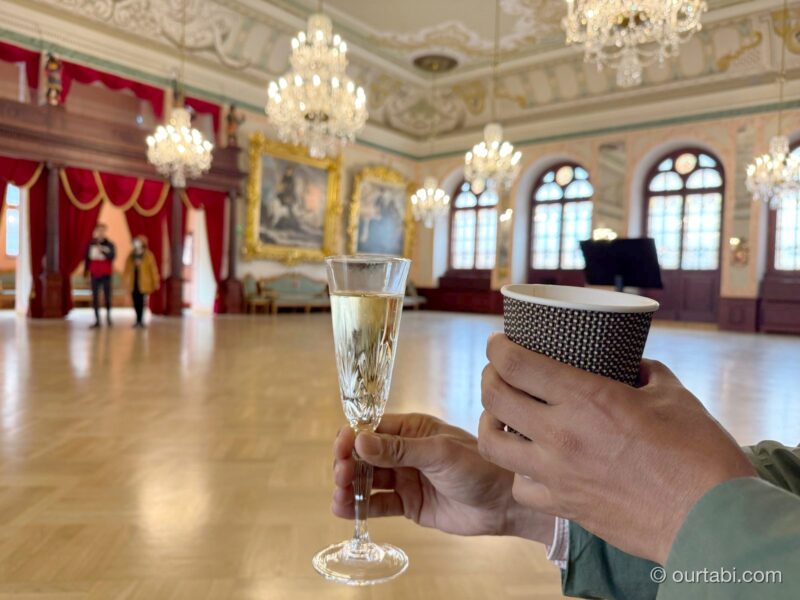 大広間でスパークリングワインのグラスとコーヒーのカップを手にしたところ