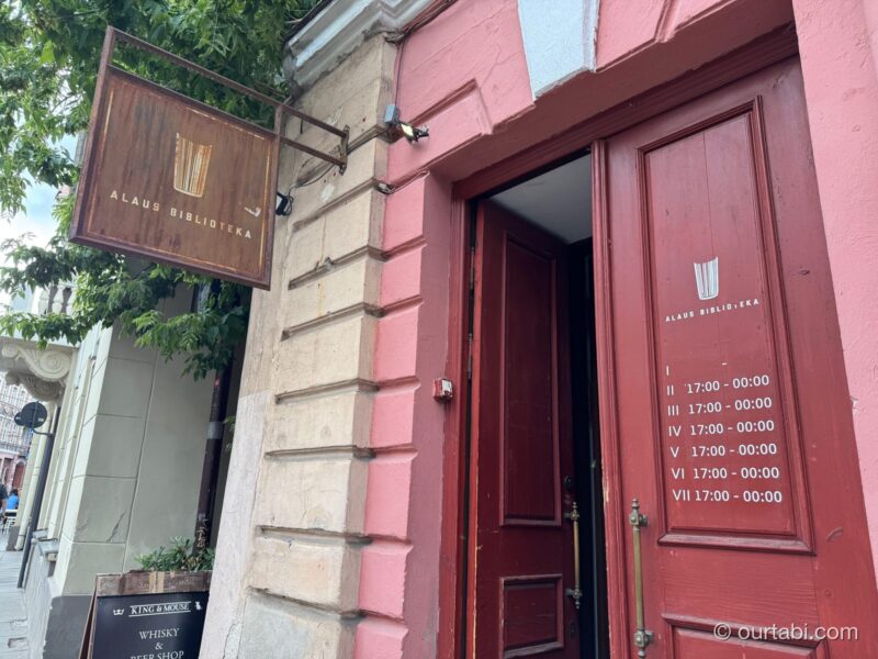 ピンクの建物の赤い扉と、Alaus Bibliotekaの看板