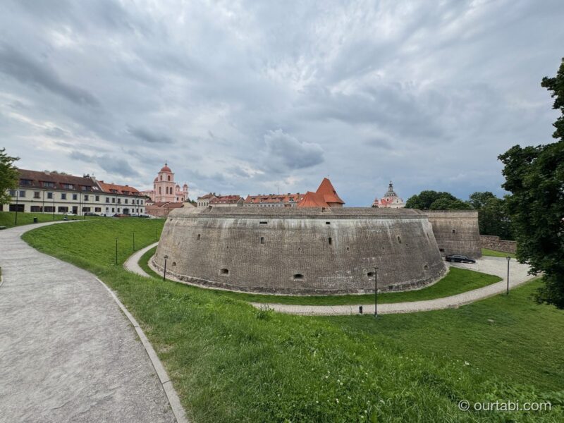 芝生の向こうに曲線を描く古い石の砲台の壁と、旧市街の建物