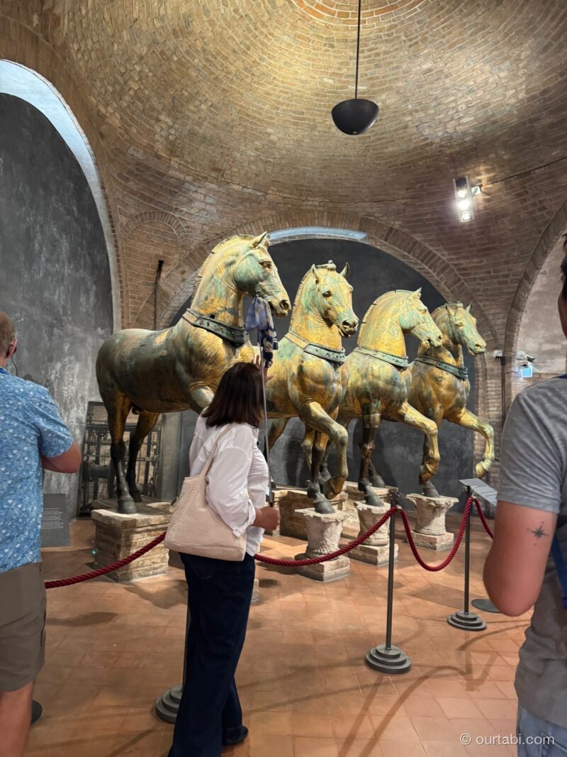 博物館の円形の部屋に展示された、4頭の金色の馬の像